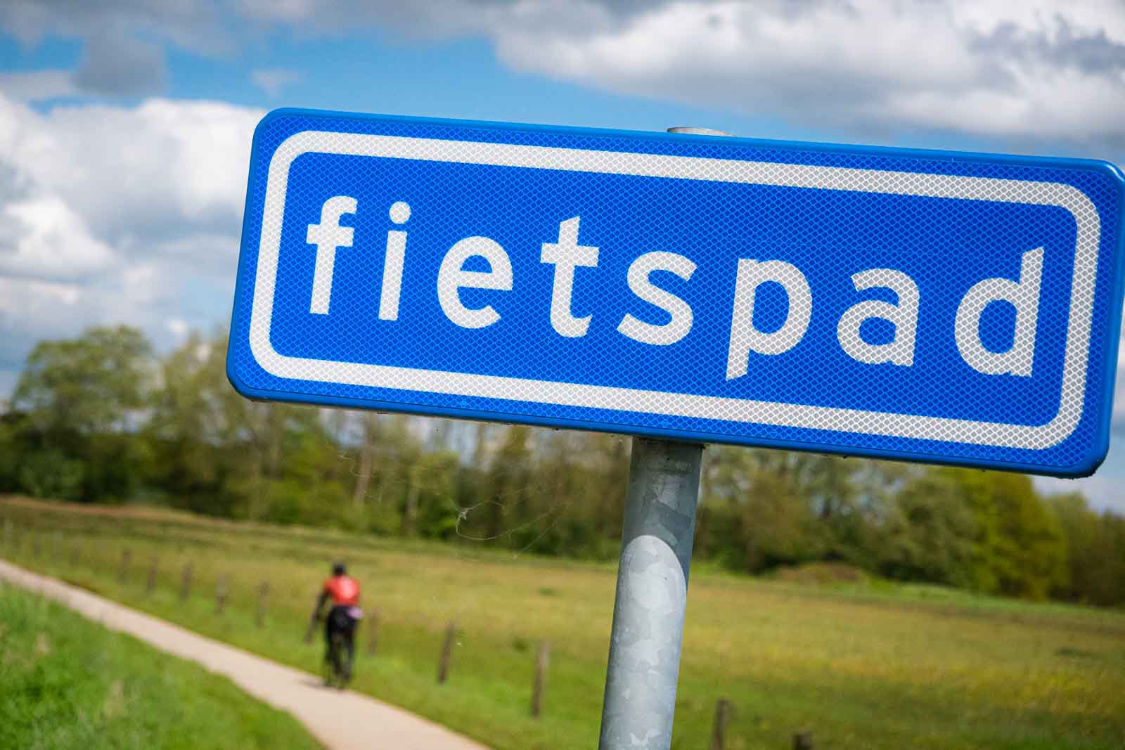 In the foreground is a sign with the inscription "Fahrradweg" (cycle path) and, blurred below, a cyclist on the cycle path