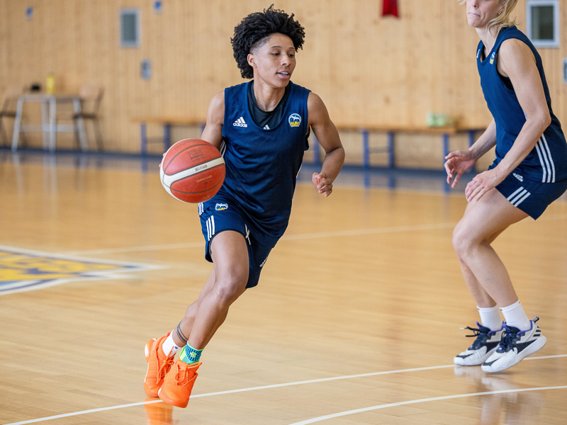 A female basketball player from Alba Berlin dribbles and goes past another player.