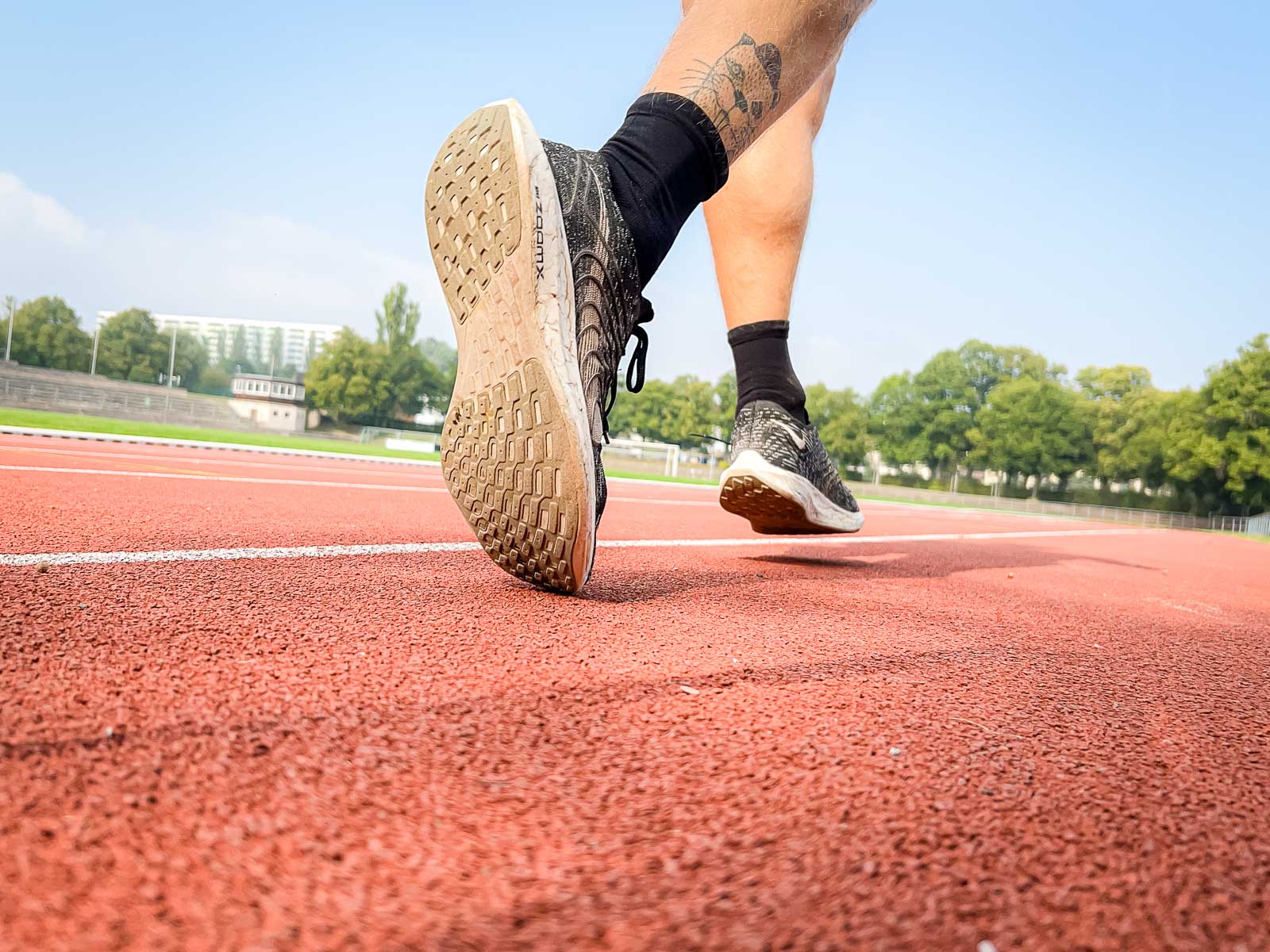 Close-up of a runner’s shoes on the red track, ready for training. The scene symbolizes determination and athletic focus.