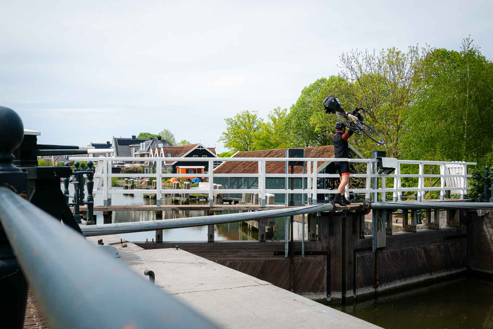 A cyclist taking part in the Race around the Netherlands carries his bike over a lock.