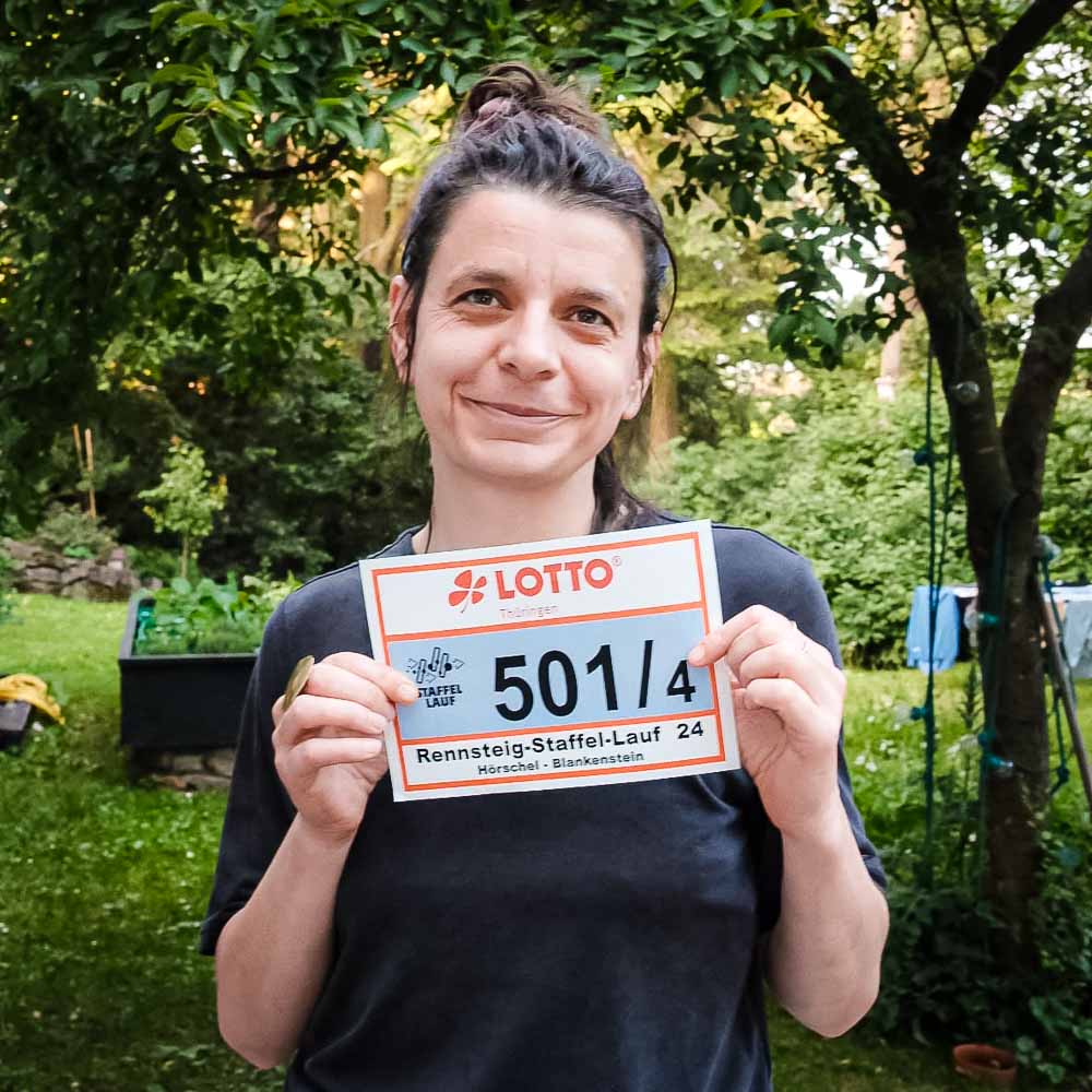 Smiling woman holds her race number plate in her hand