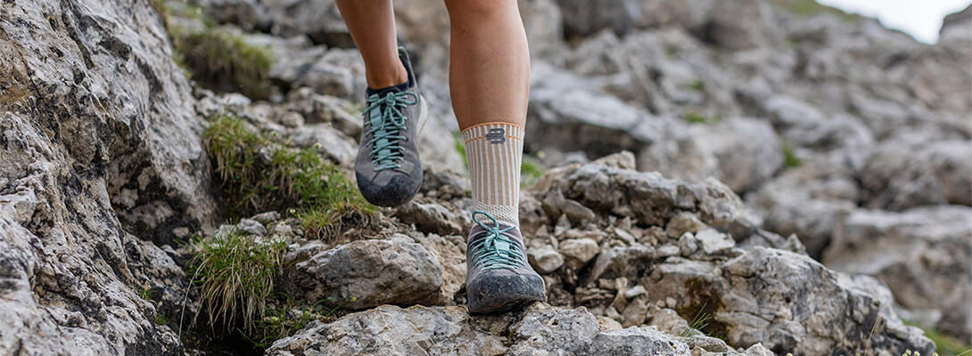 Close-up of outdoor ankle support on rocky terrain during mountain climbing.