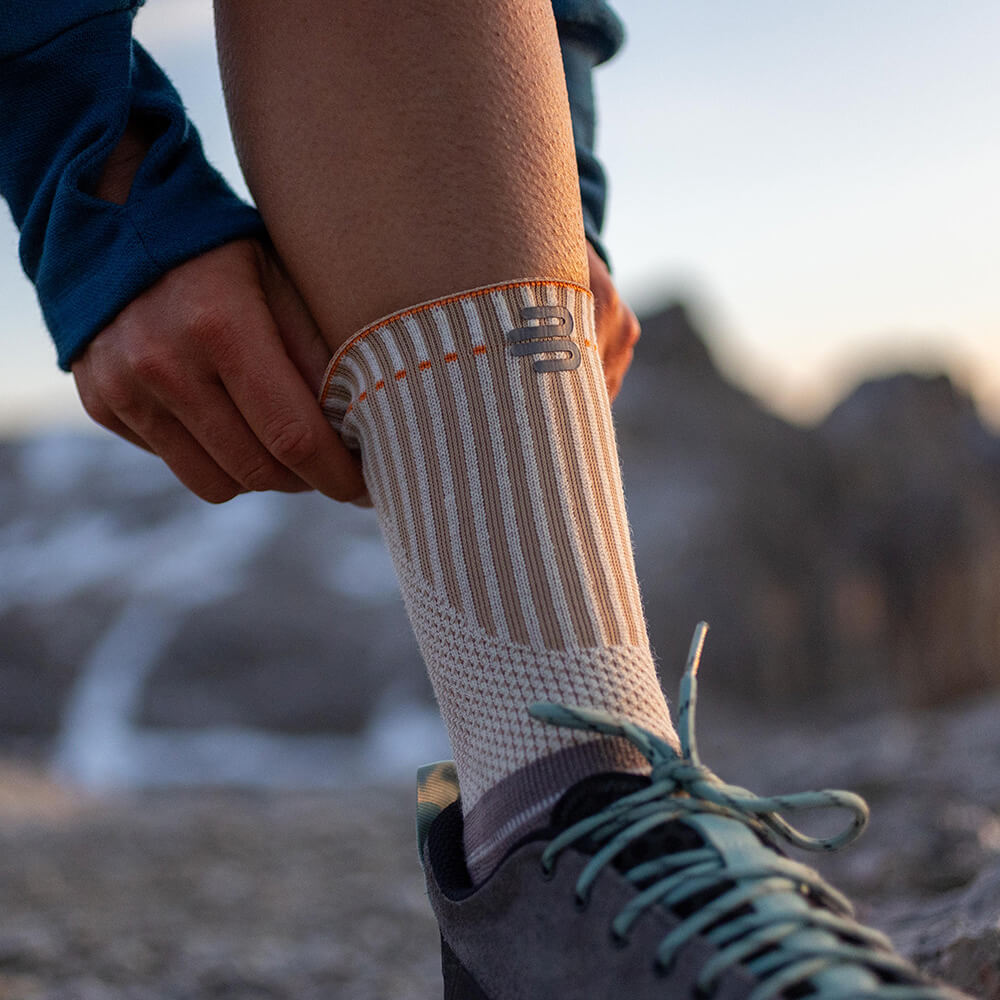 Person putting on breathable, non-slip outdoor sock, perfect for hiking and mountain climbing.