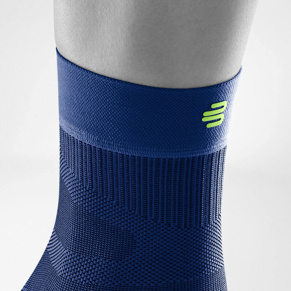 Detailed view of the upper area of ​​the dark blue Sportsleeves for the ankle including a knitted curve and logo