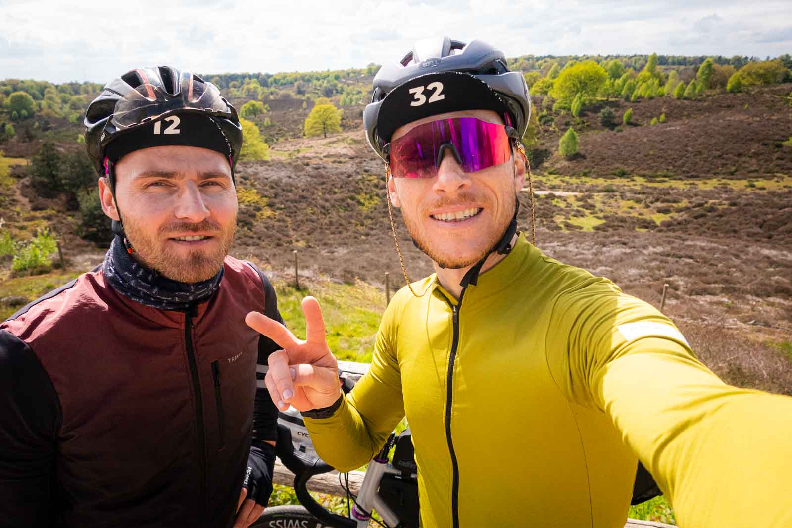 Two cyclists stand in front of a magnificent heath landscape and take a selfie